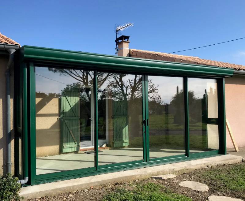Véranda sur-mesure en aluminium près de Toulouse avec deux pans de verre fixes et une large ouverture centrale 